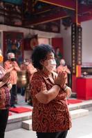 bandung, indonesia, 2020 - el visitante reza junto con los monjes frente a las ofrendas al dios foto