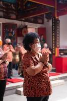 Bandung, Indonesia, 2020 - The visitor praying together with the monks in front of the offerings to the god photo