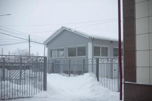 Building is in winter. One-storey warehouse on cold day. Snow outside. Snowdrifts in city after snowstorm. photo