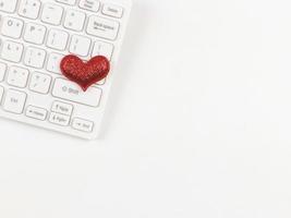 flat lay of red glitter hearts  on white computer keyboard on white  background. photo