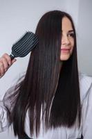 Young woman combing her long dark hair with a comb in a beauty salon photo