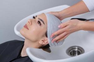 professional hairdresser washing hair of young woman in beauty salon. close up of woman's hair in beauty salon, hairstyle concept photo