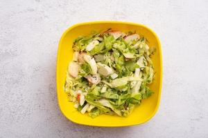 ensalada de verduras frescas y palitos de cangrejo en un recipiente de plástico. el concepto de alimentación saludable foto