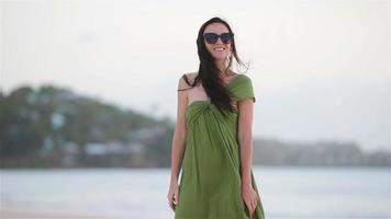 jovem mulher bonita na praia tropical. garota turista em vestido verde na praia video