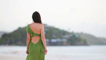 giovane bellissimo donna su tropicale spiaggia. turista ragazza nel verde dreess su il spiaggia video