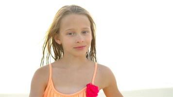 Porträt eines kleinen Mädchens, das in die Kamera blickt und im Hintergrund lächelt, schöner Himmel und Meer. Zeitlupe video