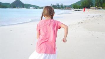 adorable niña corriendo en la playa. niño feliz disfruta de las vacaciones de verano. camara lenta video