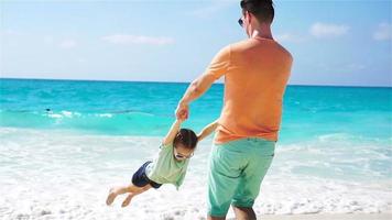 niña y padre joven divirtiéndose durante las vacaciones en la playa tropical. camara lenta video