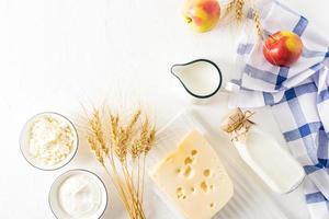 traditional fresh dairy products, ears of corn, fruit on a white background with a place for text. top view. flat styling. shavuot concept photo