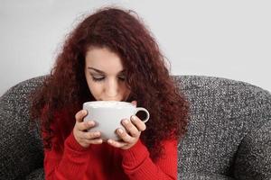 girl sipping from large cup of coffee photo