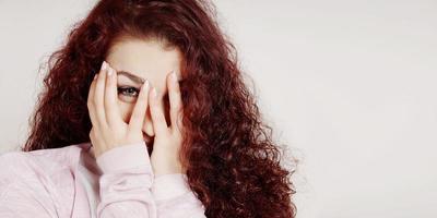 embarrassed young woman peeking through fingers photo