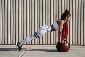 Athletic woman doing exercise push ups with med ball. Strength and motivation.Photo of sporty  woman in fashionable sportswear photo