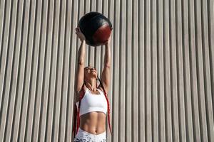 mujer atlética haciendo ejercicio con levantamientos de pelota médica sobre su cabeza. fuerza y motivación.foto de mujer deportiva en ropa deportiva de moda foto