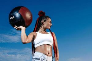 background sky. Athletic woman with med ball. Strength and motivation.Photo of sporty  woman in fashionable sportswear photo