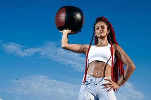 background sky. Athletic woman with med ball. Strength and motivation.Photo of sporty  woman in fashionable sportswear photo