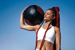 Holds on shoulder med ball. Athletic woman with med ball. Strength and motivation.Photo of sporty  woman in fashionable sportswear background sky photo