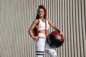 Medium shot on wall background. Athletic woman with med ball. Strength and motivation.Photo of sporty  woman in fashionable sportswear photo