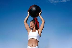 Holds on shoulder med ball. Athletic woman with med ball. Strength and motivation.Photo of sporty  woman in fashionable sportswear background sky photo