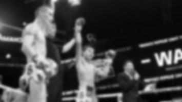 Blurred images black and white photo style of Thai boxing or Muay Thai or Kickboxing which local and foriegn boxer are fighting on the ring at indoor stage as martial art sport. Muay Thai Kick boxing