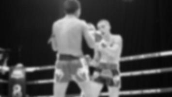 Blurred images black and white photo style of Thai boxing or Muay Thai or Kickboxing which local and foriegn boxer are fighting on the ring at indoor stage as martial art sport. Muay Thai Kick boxing