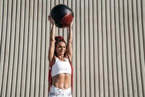 Athletic woman doing exercise with med ball raises over your head . Strength and motivation.Photo of sporty  woman in fashionable sportswear photo