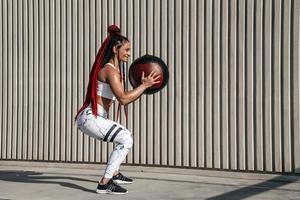 Athletic woman doing exercise squat with med ball. Strength and motivation.Photo of sporty  woman in fashionable sportswear photo