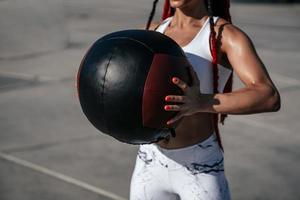 las manos se cierran. mujer atlética con balón médico. fuerza y motivación.foto de mujer deportiva en ropa deportiva de moda foto
