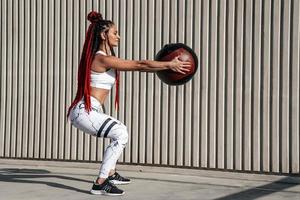 Athletic woman doing exercise squat with med ball. Strength and motivation.Photo of sporty  woman in fashionable sportswear photo