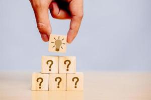 Hand holding wooden cube block in question mark what does it mean on cement table background A column of marked wooden blocks was discovered as the answer. copy space,FAQ frequently asked questions. photo