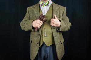 retrato de un hombre exitoso con traje de tweed sosteniendo un par de guantes de cuero marrón. concepto de estereotipo de caballero británico clásico foto
