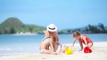familie die zandkasteel maakt bij tropisch wit strand. vader en twee meisjes spelen met zand op tropisch strand video