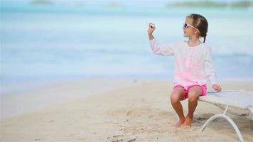 Happy little girl with toy airplane in hands on white sandy beach. Kid play with toy on the beach video