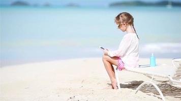 Little girl making video or photo with by her camera sitting on the sunbed