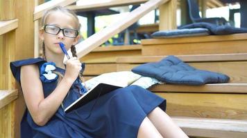 adorabile bambina della scuola con note e matite all'aperto. di nuovo a scuola. video