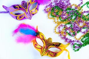 dos máscaras de carnaval con plumas y cuentas multicolores sobre fondo blanco. mardi gras o símbolo del martes gordo. foto