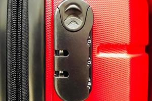 Combination lock on suitcase close-up. Concept of protecting your belongings when traveling. Red travel suitcase with secret lock. photo