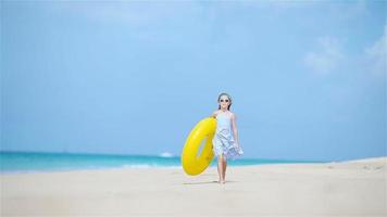 aanbiddelijk meisje met opblaasbaar rubber cirkel Aan wit strand klaar voor zwemmen video
