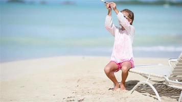 Happy little girl with toy airplane in hands on white sandy beach. Kid play with toy on the beach video