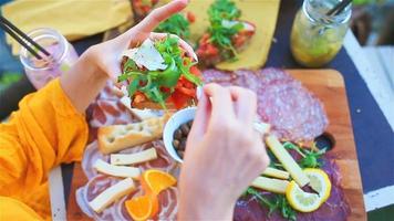 smakelijk Italiaans tussendoortje. vers bruschettes, kazen en vlees Aan de bord in buitenshuis cafe met verbazingwekkend visie in manarola, Italië video