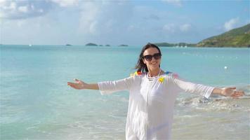 junge schöne Frau, die sich an der tropischen Küste amüsiert. glückliches Mädchen, das am tropischen Strand mit weißem Sand spazieren geht. Zeitlupe video