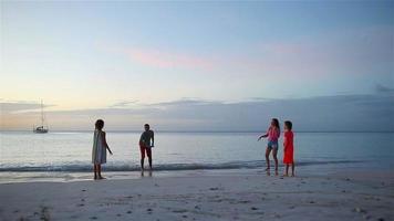 gelukkige familie spelen met vliegende schijf op het strand bij zonsondergang video