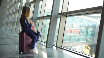 Entzückendes kleines Mädchen mit Gepäck am Flughafen, das auf das Einsteigen wartet und aus dem Fenster schaut video