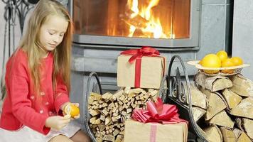 Heureuse jolie fille ouvrant le cadeau de Noël près de la cheminée
