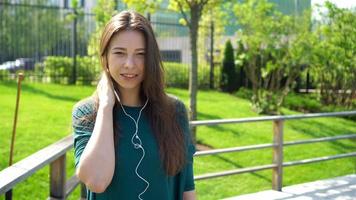 Young woman listening the music by headphones. Attractive female with cute smile with mobile phone while rest in cafe video