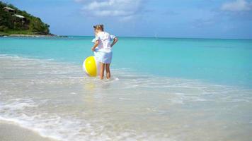 jolie petite fille jouant avec un ballon sur la plage, sports d'été pour enfants à l'extérieur video