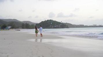 giovane coppia sulla spiaggia tropicale con sabbia bianca e acqua turchese dell'oceano all'isola di antigua nei Caraibi video