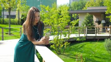 Young woman listening the music by headphones. Attractive female with cute smile with mobile phone while rest in cafe video