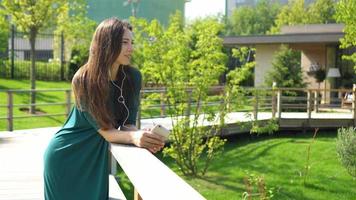 mujer joven escuchando la música con auriculares. mujer atractiva con una linda sonrisa con teléfono móvil mientras descansa en el café video