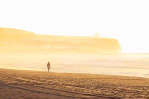 Woman walk on golden sand beach of portstewart strand by with castlerock lighthouse backgorund. Wild coast of northern ireland photo