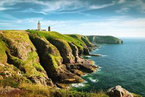 vista panorámica del pintoresco paisaje costero con un faro tradicional en la famosa península de cap frehel en la cote d'emeraude, comuna de plevenon, cotes-d'armor, bretagne, norte de francia foto